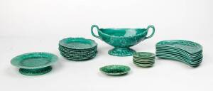 A suite of Wedgwood green leaf patterned majolica ware includes comport, tazza, 8 plates & 8 crescent shaped side plates, plus 7 assorted French majolica dishes. (25 items)