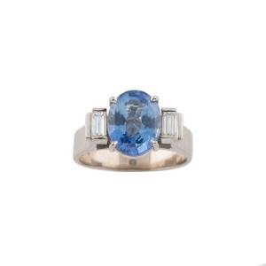 A sapphire and diamond ring, the oval blue sapphire of estimated weight 4.00 carats, set either side with a baguette diamond of total estimated weight 0.30 carat, 18ct white gold, size S &frac12;.