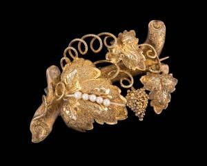 A gold foliate brooch, of grape, vine leaf and tendril design. Yellow gold. Length 55mm.