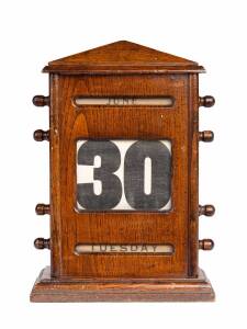 A desk calender housed in an English oak case, early 20th Century. 27cm high