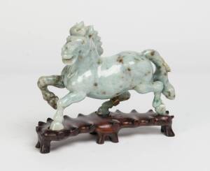 A Chinese carved jade horse adorned with 14ct gold band studded with emerald rubies & sapphires, early 20th Century. The horse 19cm high, 20cm wide, 5cm deep