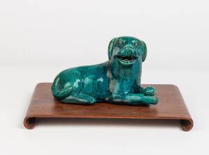 A Chinese export green glazed porcelain figure of a dog with a wooden stand, late Qing dynasty, 19th-20th century