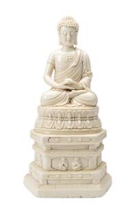 A large Chinese Dehua figure of Buddha covered in a creamy-white glaze, seated on a lotus throne atop a tiered pedestal. 20th Century. 33cm high  