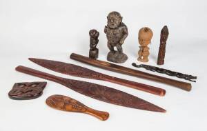 A collection of tribal ornaments including Maori patu, fishhook necklace, paddles etc.  