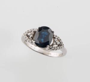 A sapphire and zircon dress ring, the central oval sapphire off approximate weight 2.70 carats and set either side with small white zircons. 14ct white gold. Ring size J1/2.