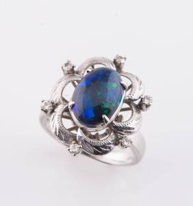 An opal and diamond ring, the central oval black opal cabochon measuring 11mm x 7.1mm. White gold. Ring size P.