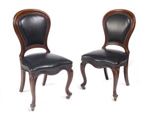 A pair of black leather upholstered side chairs.