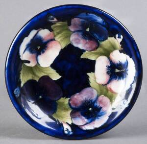MOORCROFT: Pansy patterned pottery boal on blue ground. Original paper label "By Appointment Potter To H.M. the Queen"