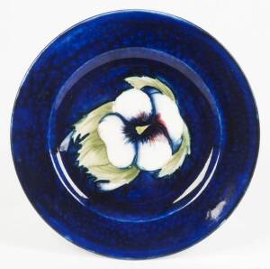 MOORCROFT: Pansy patterned plate. Rich blue ground decorated with a single white pansy. Mid 20th century,19cm. VG condition