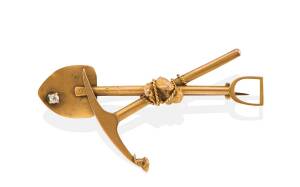 A gold miner’s brooch, the crossed pick and shovel set with gold nuggets and a single old brilliant cut diamond. Yellow gold. Weight 4.09 grams. Length 5.4cm.