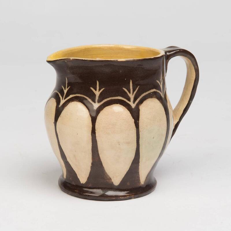 Marguerite Mahood (1901-1989) A wheel thrown glazed earthenware jug decorated with leaf shaped cream panels