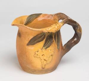 Peggy Whiting A saffron glazed earthenware jug with applied wattle leaves