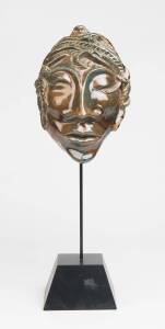 M Wood A glazed earthenware mask, on a later ebonsied stand