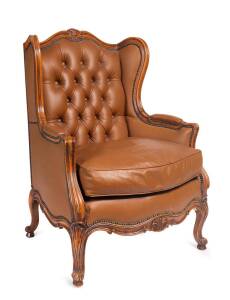 A wing back arm chair with brown leather studding and carved walnut frame.&nbsp;