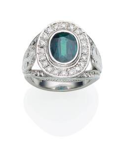 A green sapphire and diamond ring, the oval green sapphire of estimated weight 3.29 carats, surrounded by twenty brilliant cut diamonds, estimated weight 0.60 carats. Platinum. Weight 24.3 grams. Size Q&nbsp;&frac12;.