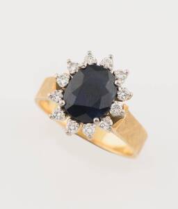 A sapphire and diamond flowerhead cluster ring, the blue sapphire measuring 9.4 x 7.5mm, on a textured gold shank. 18ct yellow gold. Weight 6.08 grams. Size N ½. 