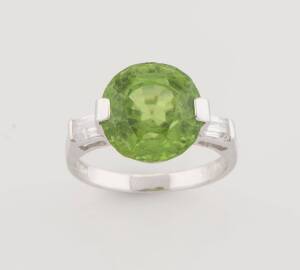 A peridot and diamond ring, the periodot of known weight 7.18 carats, with baguette diamond shoulders, total known weight  0.30 carats. 18ct white gold. Weight 4.32 grams. Size L ½.