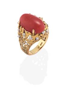 A coral and diamond ring, the oval red coral cabochon measuring 20 x 13.2 x 8.84mm, small single cut diamonds to textured mount. 14ct yellow gold. Weight 13.99 grams. Ring size O.