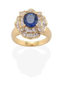 A sapphire and diamond cluster ring, the oval blue sapphire measuring 7.96 x 7.04 x 3.44mm, estimated weight 1.54 carats, in a stepped mount set with marquise and brilliant cut diamonds. 18ct yellow gold. Weight 6.9 grams. Ring size M.