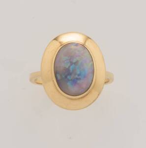An opal ring, the oval opal cabochon set in a wide gold frame. 18ct yellow gold. Weight 7.4 grams. Size O &frac12;.&nbsp;