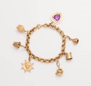 A charm bracelet, the 18ct yellow gold belcher link bracelet hung with seven charms of varying carats. Total weight 28.66 grams. Length 19cm.&nbsp;