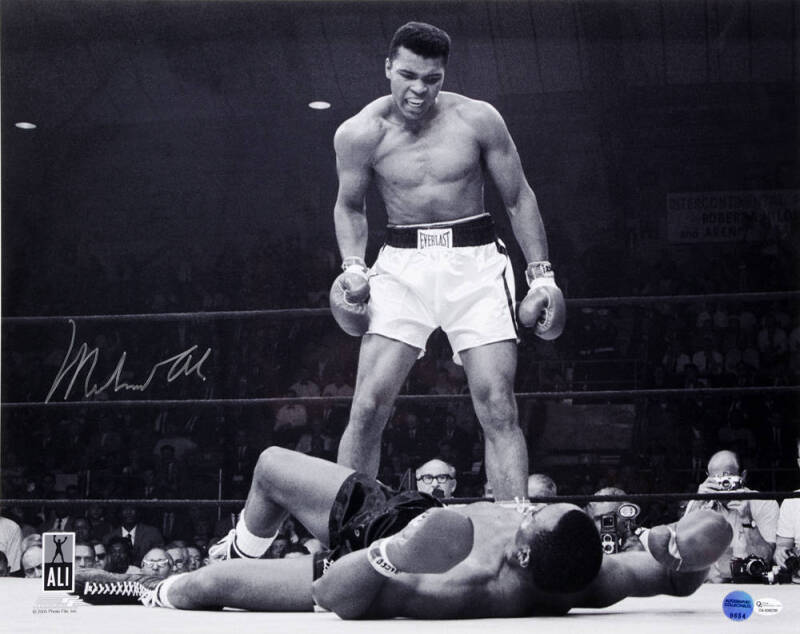 MUHAMMAD ALI, signed b/w photograph of Ali standing over Sonny Liston, size 51x41cm. With 'Online Authentics' No.OA-8090308.