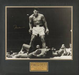 MUHAMMAD ALI, signed b/w photograph of Ali standing over Sonny Liston, window mounted with plaque, framed & glazed, overall 72x70cm.