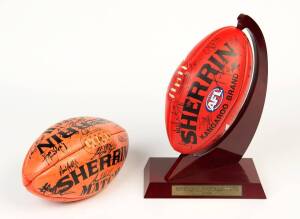 SIGNED FOOTBALLS, noted football signed by 2004 Essendon team with display stand; plus football signed by c2009 Brisbane team. [Proceeds to Kids Under Cover].