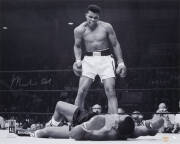MUHAMMAD ALI, signed b/w photograph of Ali standing over Sonny Liston, size 51x41cm. With 'Online Authentics' No.OA-8090295.