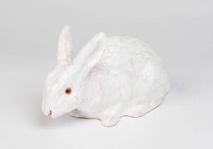 A white glazed terracotta model of a rabbit with pink glass eyes, French, 20th centuryStamped to the base. 17cm high, 27cm long