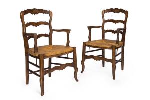 A pair of French provincial style carved beech elbow chairs, rush seats