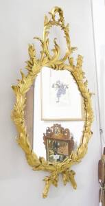 An oval floral giltwood wall mirror. 120 x 70cm