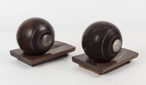 LAWN BOWLS: Pair of Lignum Vitae lawn bowls with silver button engraved "PMBC/ Pair Trophy, F.T.warren, 1901", mounted on wooden stands for use as bookends.
