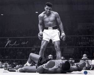 MUHAMMAD ALI, signed b/w photograph of Ali standing over Sonny Liston, size 51x41cm. With 'Online Authentics' No.OA-8090319.