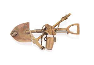 A gold miner's brooch, crossed pick and shovel, bucket and  gold nugget, marked 9ct. Weight 3.33 grams. Length 45mm.