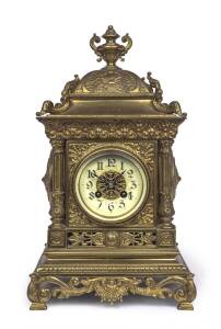 An ornated brass cased mantel clock with enamel dial