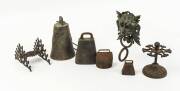 A collection of bronze and cast iron cowbells and stands