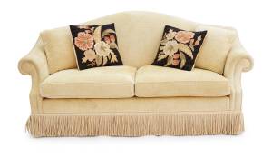 A two seater sofa with cream upholstery with 4 cushions
