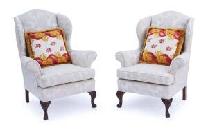 A matched pair of George II style wingback armchairs with cushions