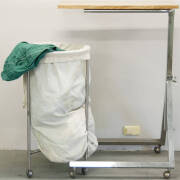 Adjustable table on trolley, and laundry basket on metal trolley.