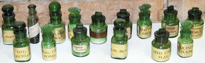 CHEMIST'S DISPENSING BOTTLES, green glass with painted & printed labels, four with ornate stoppers, 5cm. All in good condition.