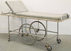 Patient transport padded bed on wheeled trolley.