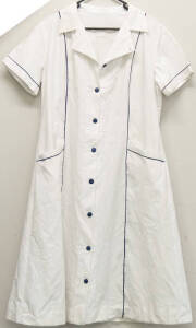 A pair of white nurses dresses with blue piping.