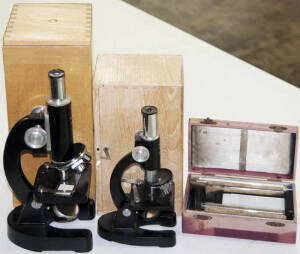 Small microscope with spare lens in small wooden box; includes 4 slides. Together with Microscope in wooden box with "Hellige-Normal-Haemometer" red box containing lens, measures and slides.