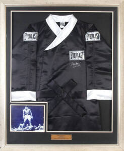 MUHAMMAD ALI, black "Everlast" boxing robe signed "Muhammad Ali aka Cassius Clay", window mounted with photo of Ali standing over Sonny Liston, framed & glazed, overall 89x110cm. With CoA.