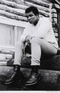 MUHAMMAD ALI, photograph titled "Muhammad Ali, Deer Lake, PA, August 1974. MA16 Sitting On Logs" by Peter Angelo Simon, silver gelatin print, signed by the photographer lower right, size 40x50cm.