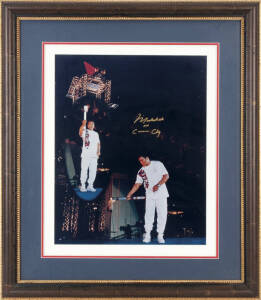 MUHAMMAD ALI, colour photograph of Ali carrying 1996 Olympic Torch, signed "Muhammad Ali aka Cassius Clay", window mounted, framed & glazed, overall 67x77cm. With CoA.