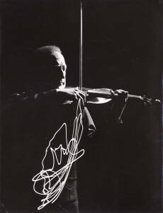 Gjon Mili [1904-1984] original silver gelatin print time-lapse photograph of Heifetz performing in a darkened room with a light attached to the end of his bow; 1952, with studio stamp and manuscript endorsements on reverse. 