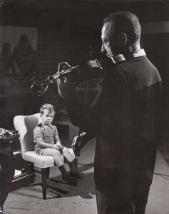 Unknown Photographer: Large original silver gelatin photograph of Heifetz playing violin with his young son, Jay [Joseph] looking-on. A cropped version of the image took up a whole page in the June 4th, 1960 edition of The Saturday Evening Post, accompany