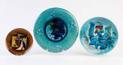 Two copper and enamel plates by Jean Ames, 20th century, one titled "Blue Cock", the other "Balance", together with an Austrian Secessionist majolica glazed platter, the platter &nbsp;27.5cm diameter. (3 items). Used as coffee table and decor dishes in the Los